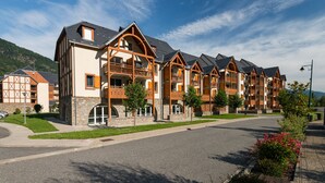 A row of multi-story buildings with balconies, stone foundations, and a clear sky. - Résidence Lagrange Vacances le Belvédère (Saint-Mamet)