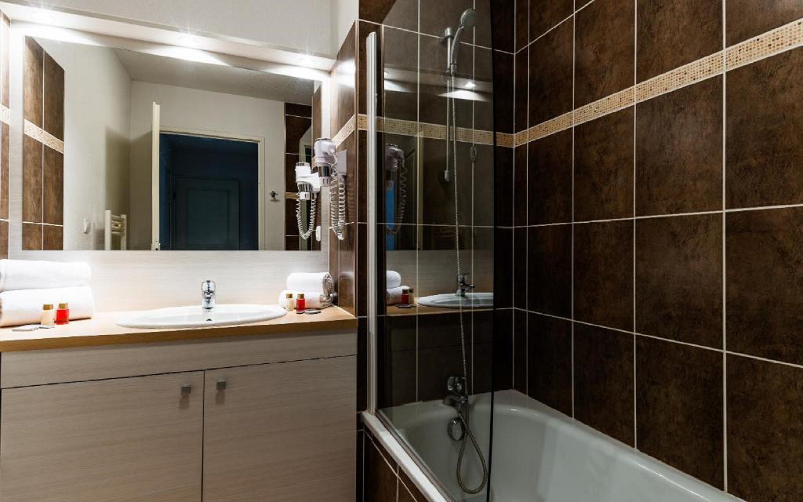 Un baño moderno con un espejo grande, un lavamanos, una ducha y una bañera.