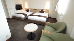 A hotel room with two beds, a TV, a small table, and two green armchairs. - Hotel Arca Torre Roppongi (Tokyo)