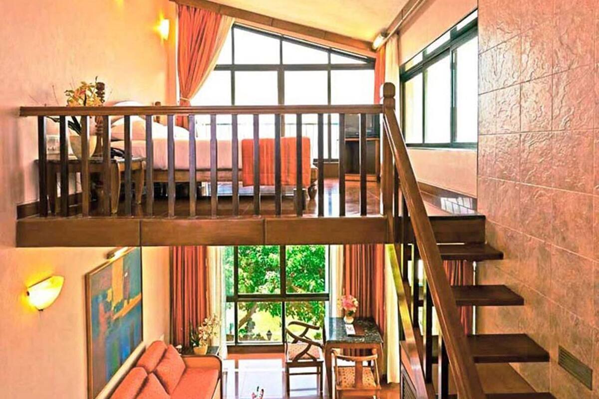A spacious interior with a staircase, a sofa, a coffee table, and a painting on the wall.