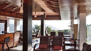 Un interno moderno con travi in legno a soffitto, un'area bar e posti a sedere con vista sull'esterno.