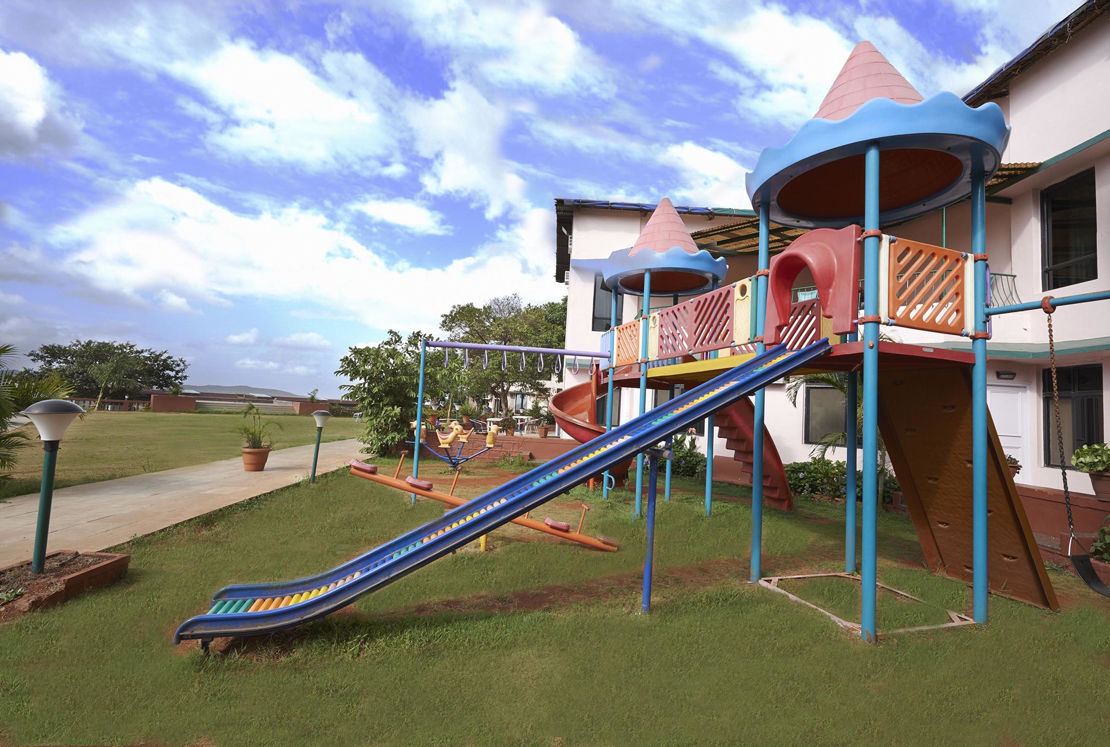 Un parc infantil amb tobogan, elements per escalar i cadira de balanceig.