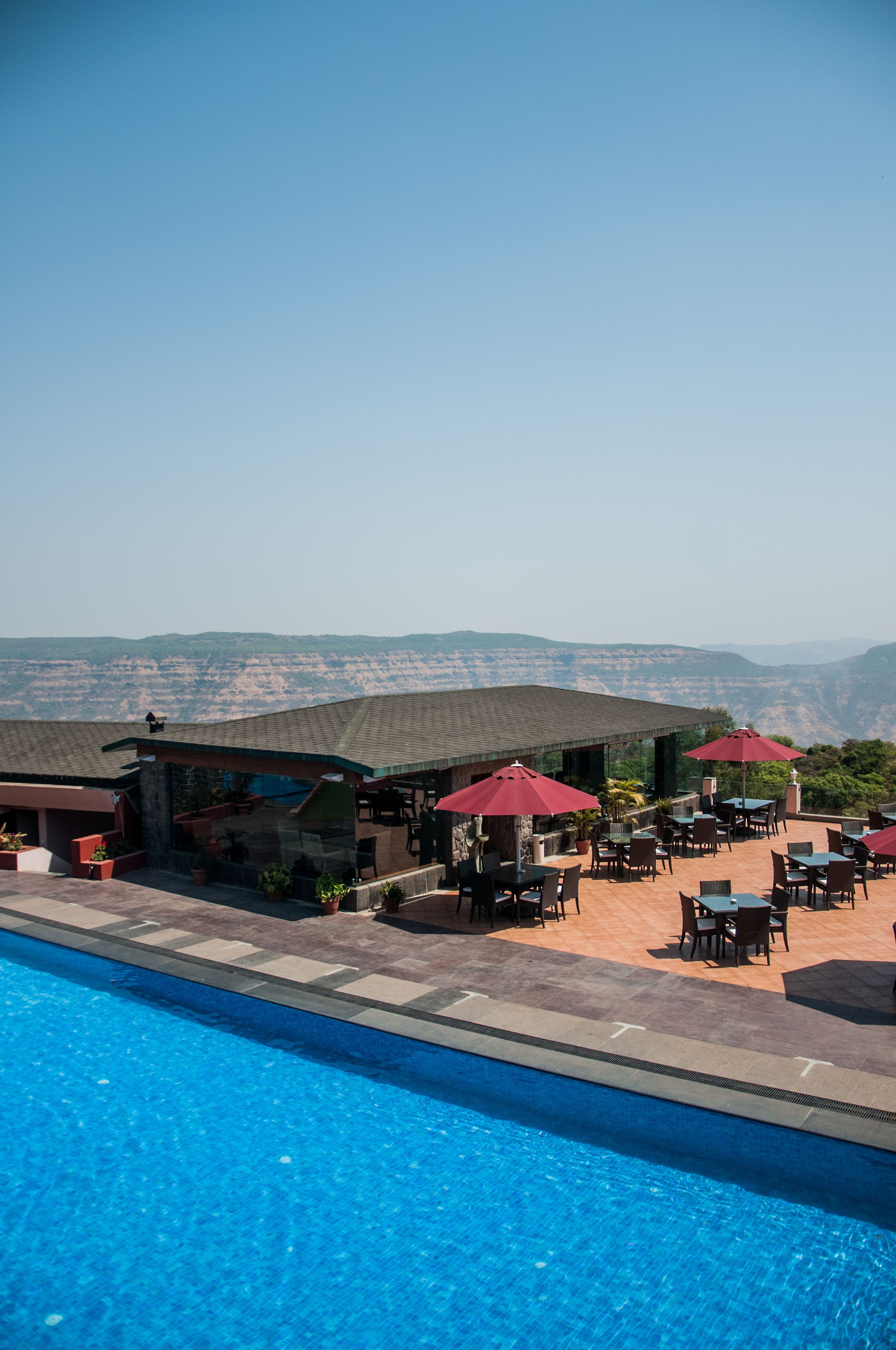 Ein Poolbereich mit Sitzgelegenheiten im Freien und Blick auf die Berge.