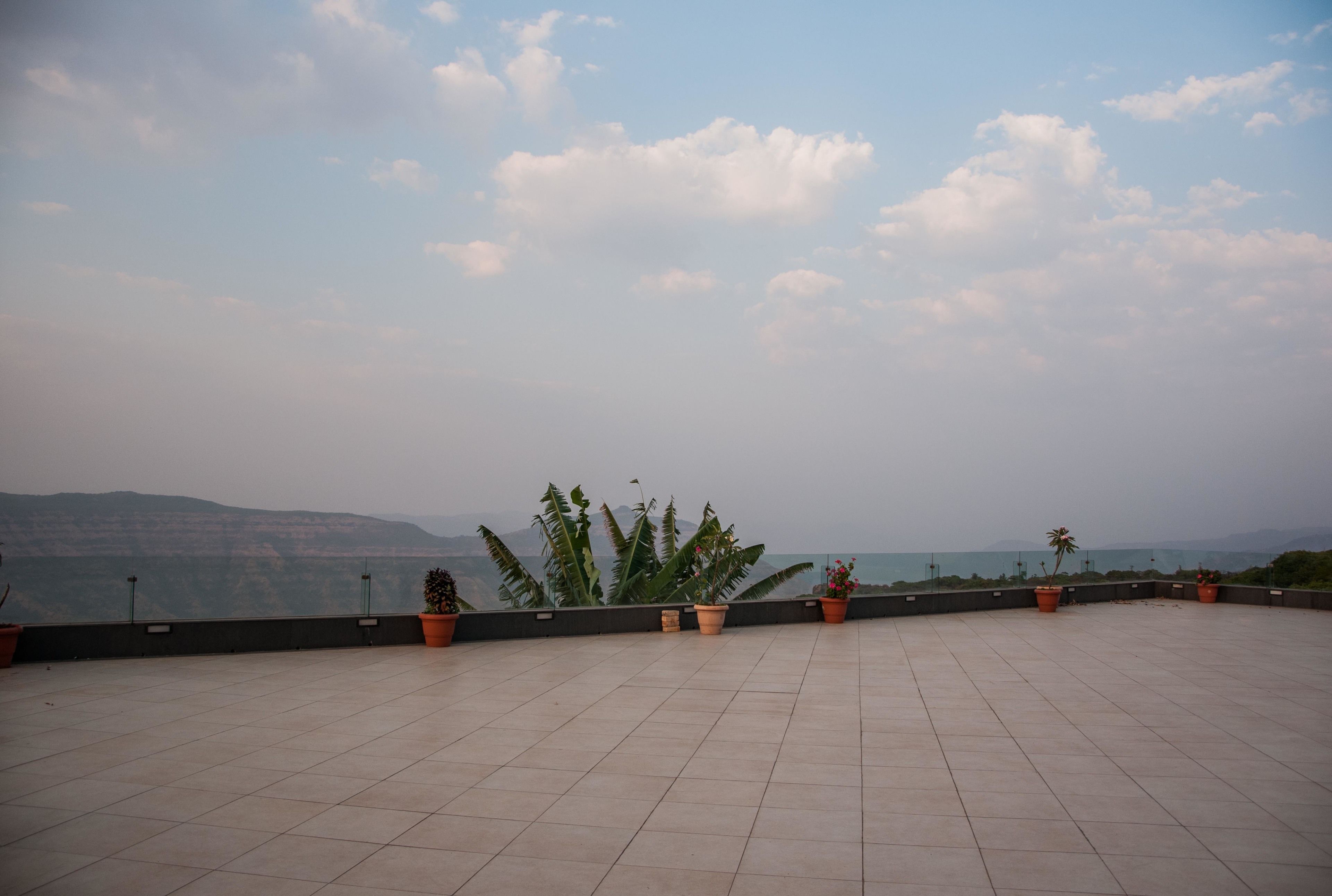 A rooftop terrace with potted plants and a view of distant mountains.