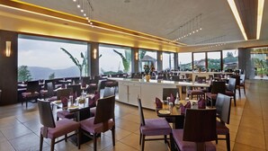 Un'ampia sala da pranzo con soffitti alti, grandi finestre e illuminazione moderna.