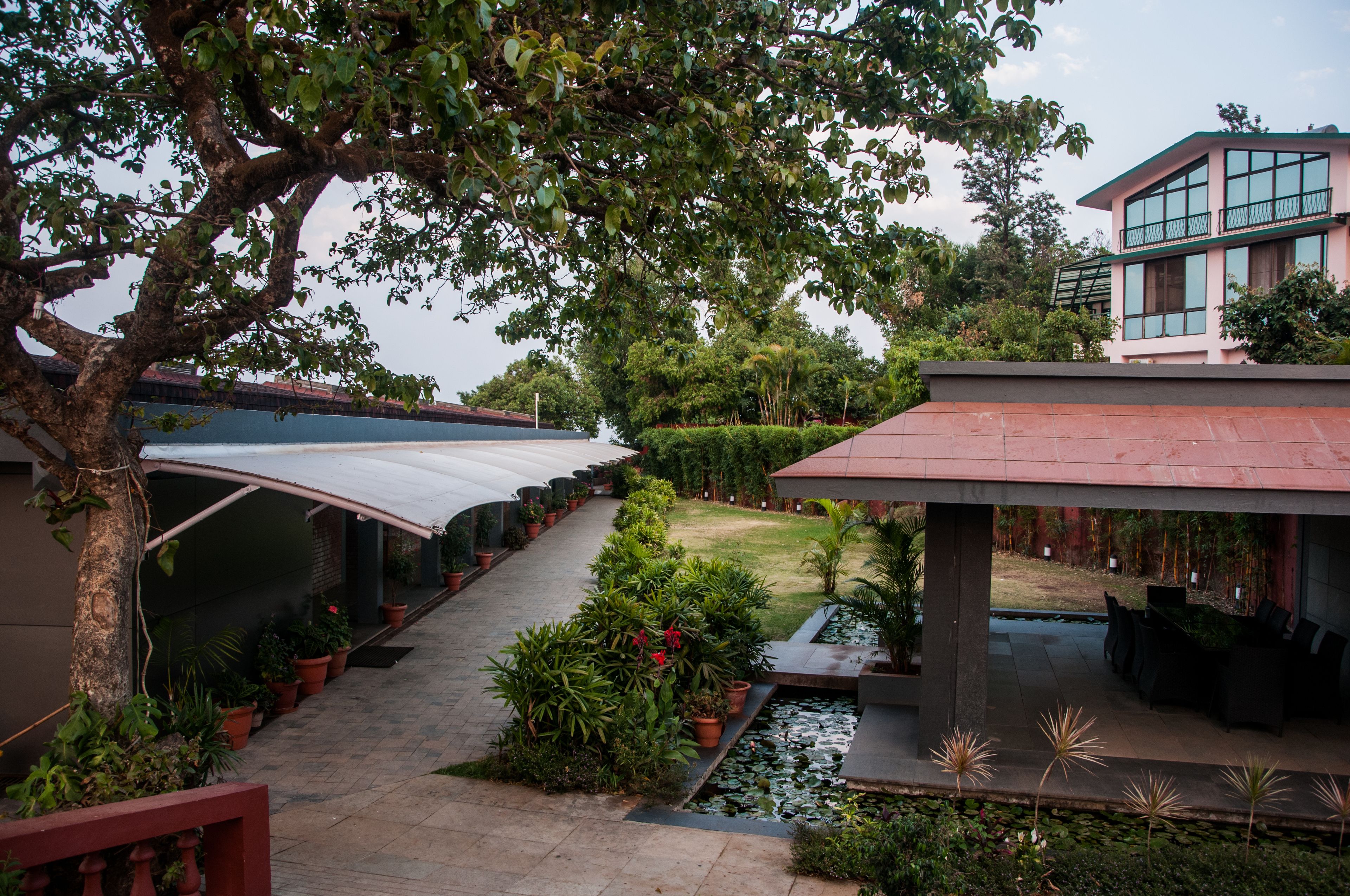 A courtyard with a covered walkway, a water feature, and a building with large windows.