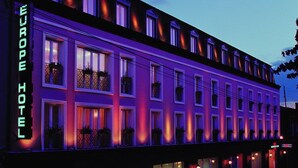 A hotel with a classic facade, multiple windows, and a neon sign indicating it's a hotel. - Europe Hotel (Yerevan)