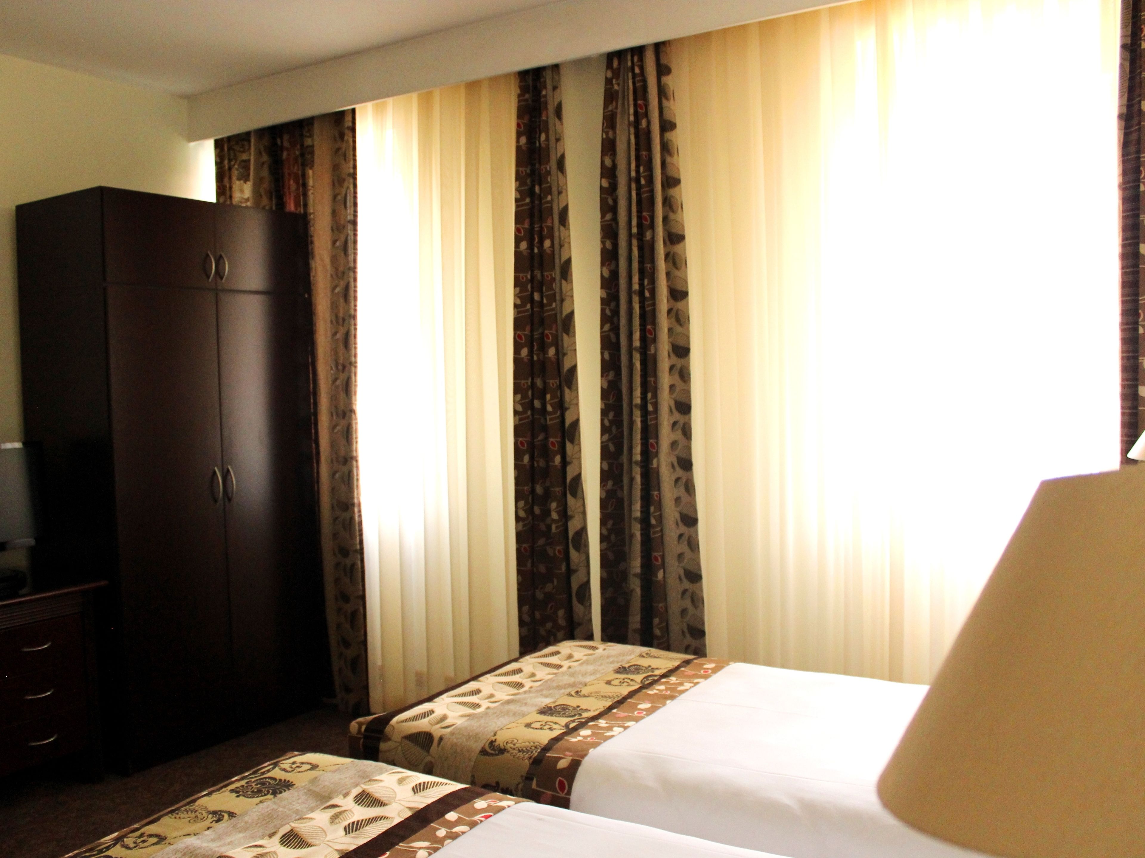 Una habitación de hotel con dos camas, un armario y cortinas.