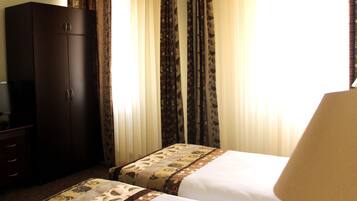 Una habitación de hotel con dos camas, un armario y cortinas.