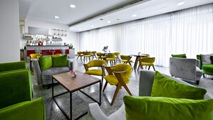 A modern hotel lobby with green and gray seating, a kitchen area, and large windows with sheer curtains. - Europe Hotel (Yerevan)