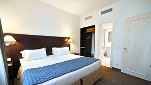 A hotel room with a large bed, a wardrobe, and a bathroom visible through an open door. - Europe Hotel (Yerevan)