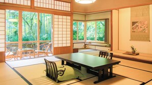A traditional Japanese room with tatami flooring, a low table, and sliding doors. - Arai Ryokan (Izu)