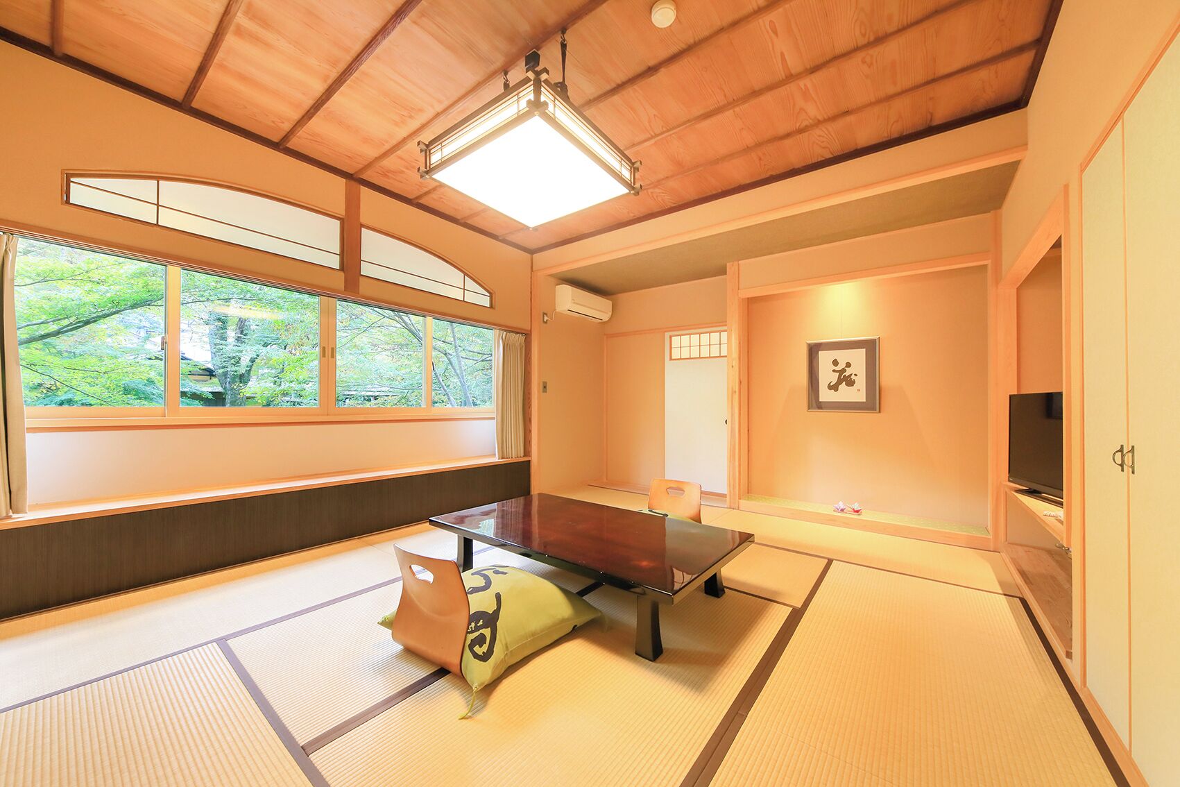 A traditional Japanese room with tatami flooring, a low table, and a television.