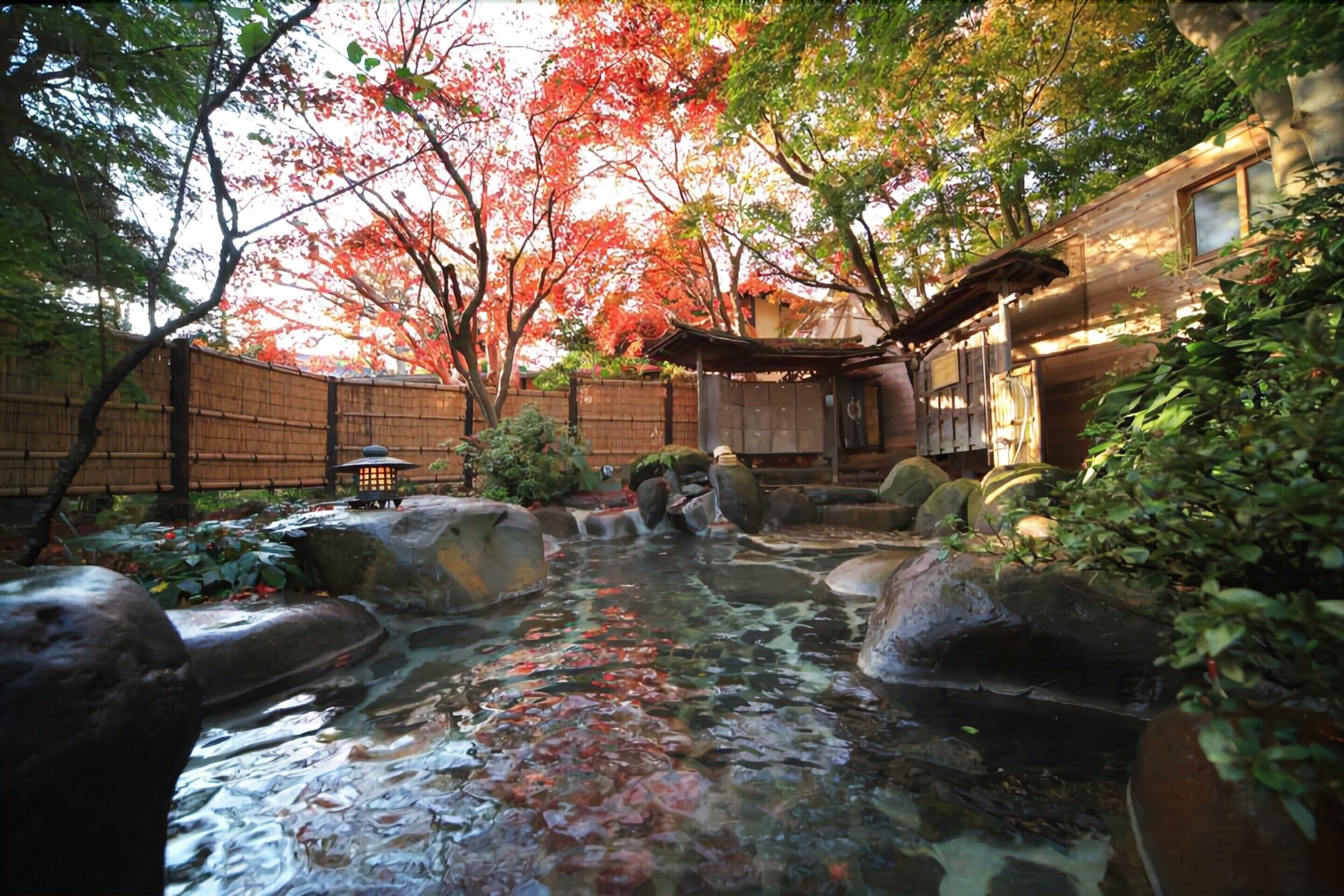 A traditional Japanese garden with a koi pond, bamboo fence, and a wooden building.