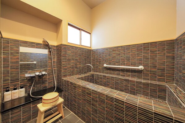 A modern bathroom with a glass-enclosed shower, a vanity with a mirror, and a small stool. - Arai Ryokan (Izu)