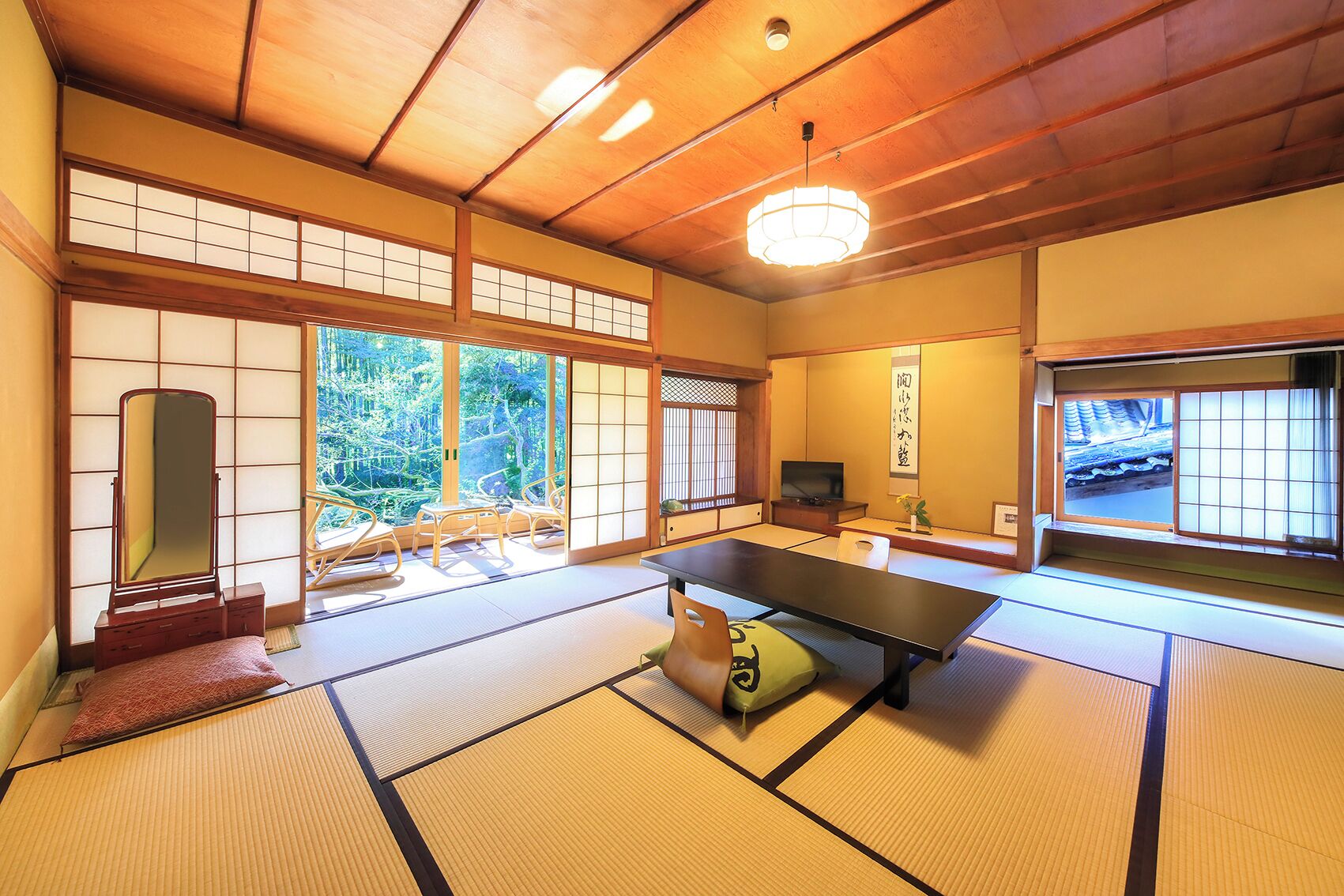 A traditional Japanese room with tatami flooring, a low table, a mirror, and sliding doors.
