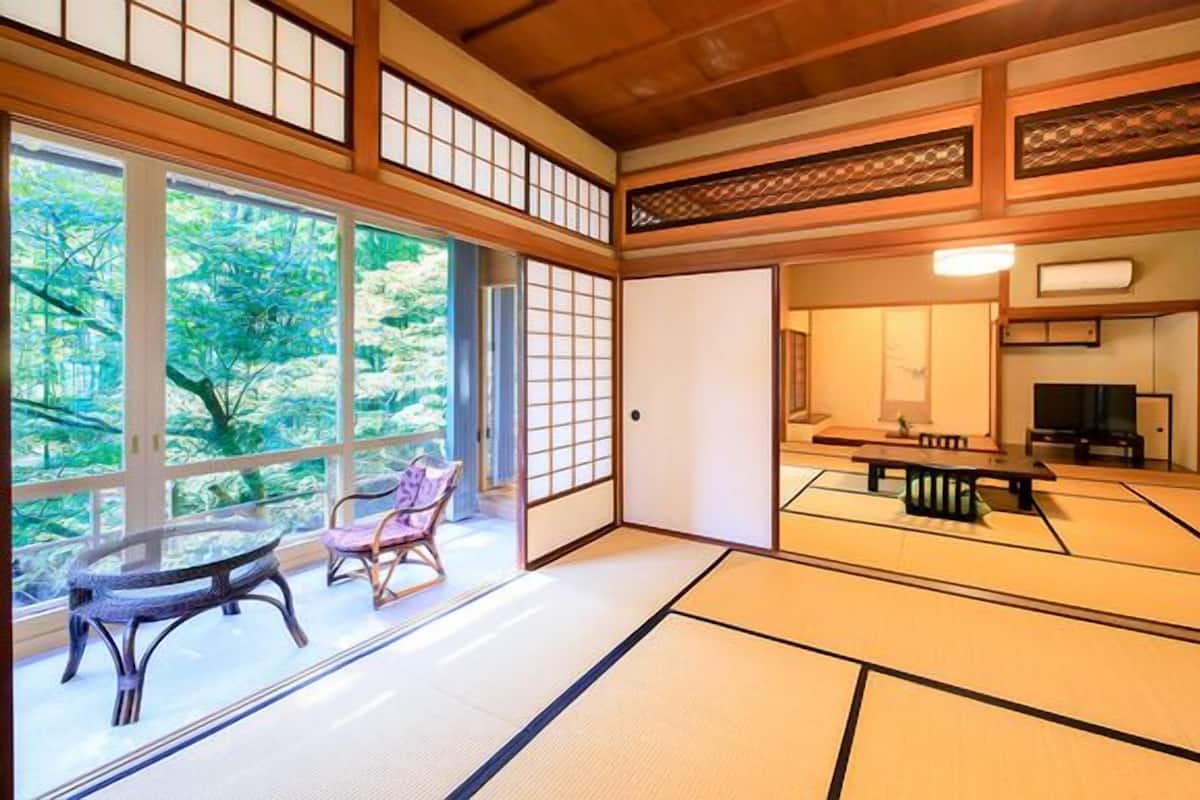 Ein traditioneller japanischer Raum mit Tatami-Bodenbelag, einem niedrigen Tisch, einem Stuhl und einer Schiebetür.