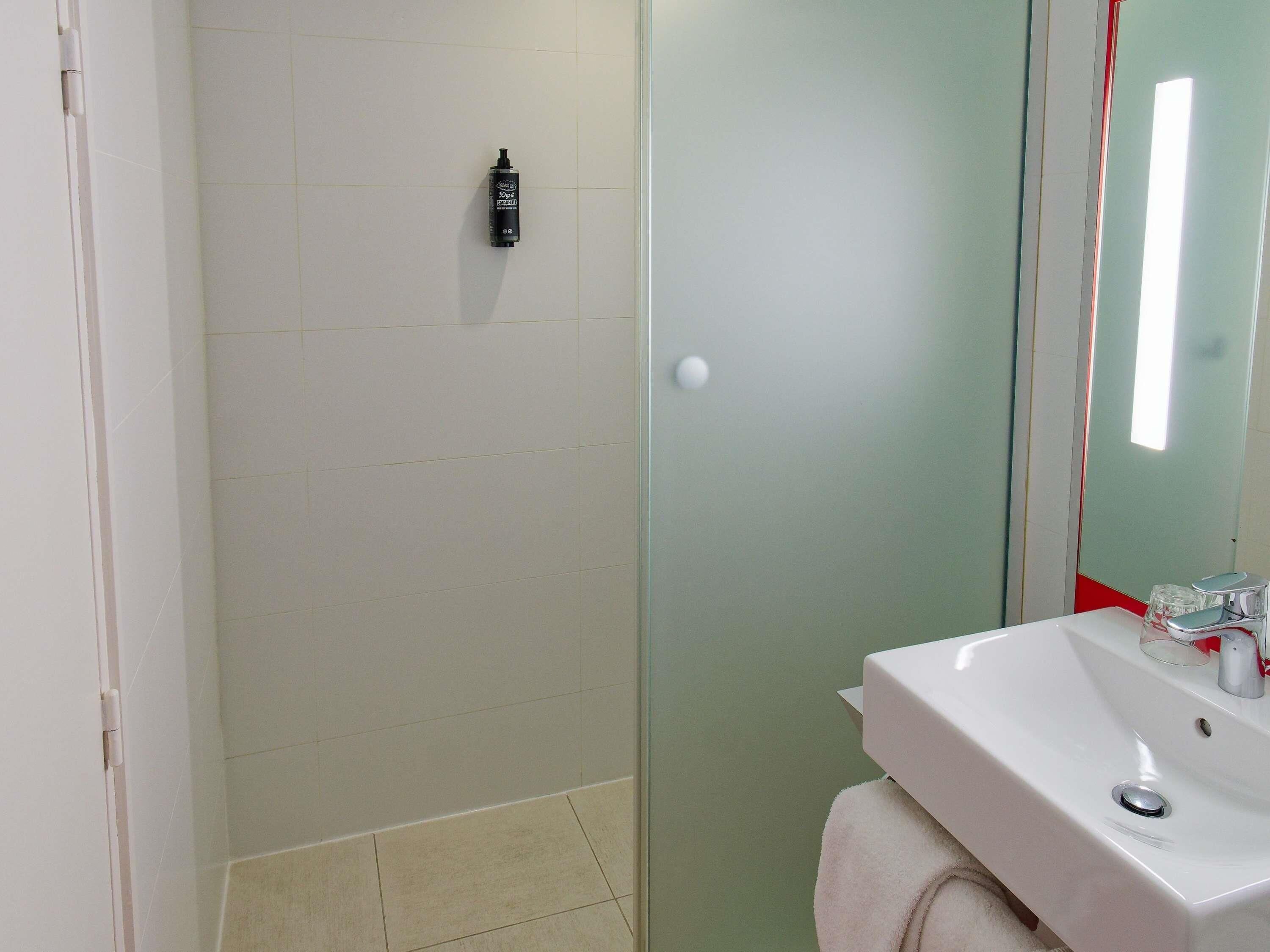 Un bagno con lavandino bianco, uno specchio e zona doccia.