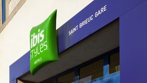Placa de hotel com 'ibis Styles' e 'HOTEIS' escrito.