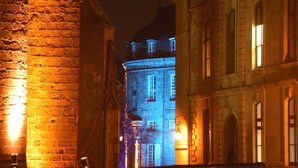 Um edifício histórico com janelas iluminadas e fachada de pedra à noite.