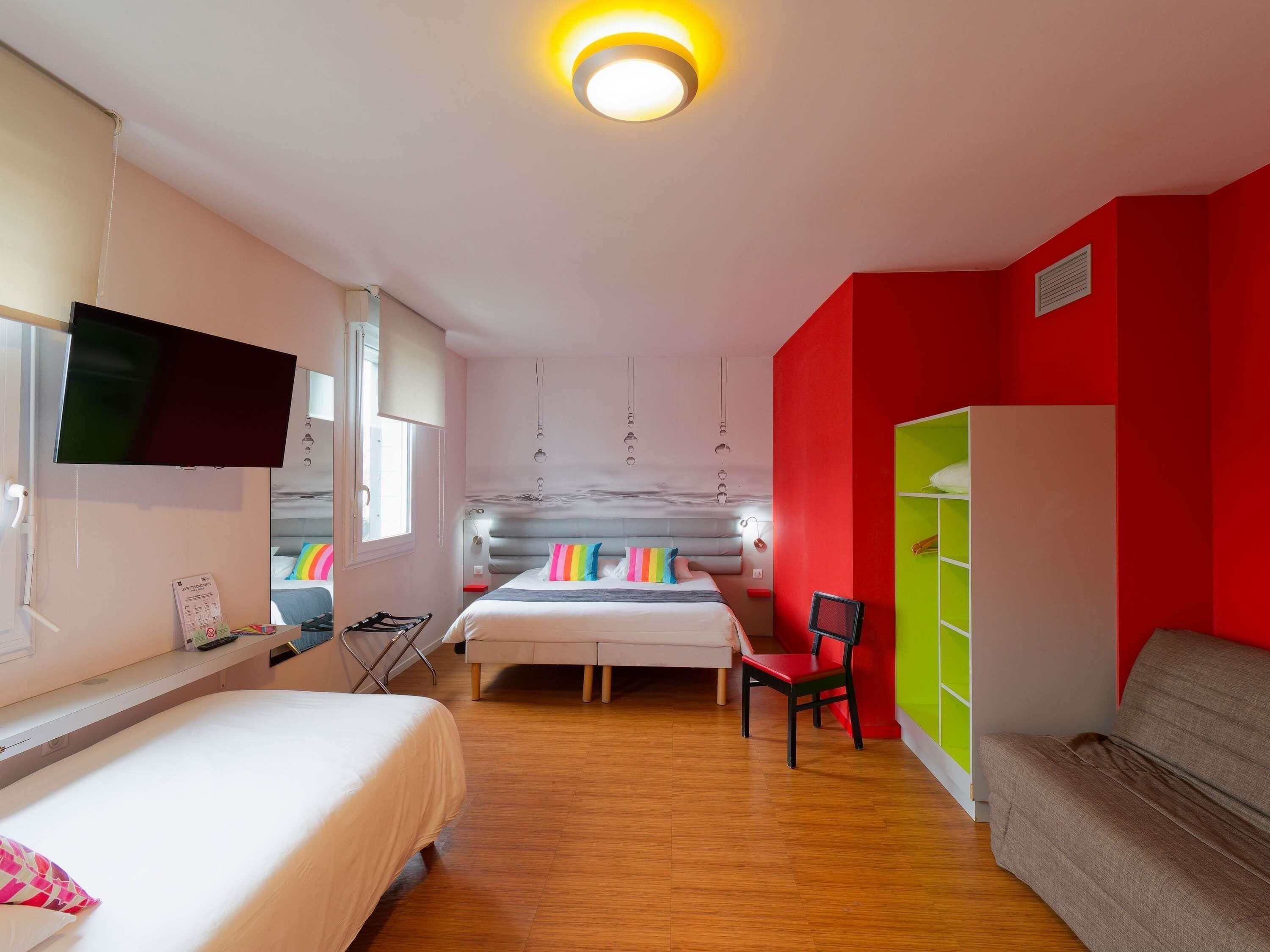 A modern hotel room with a bed, a television, a desk, and a wardrobe.
