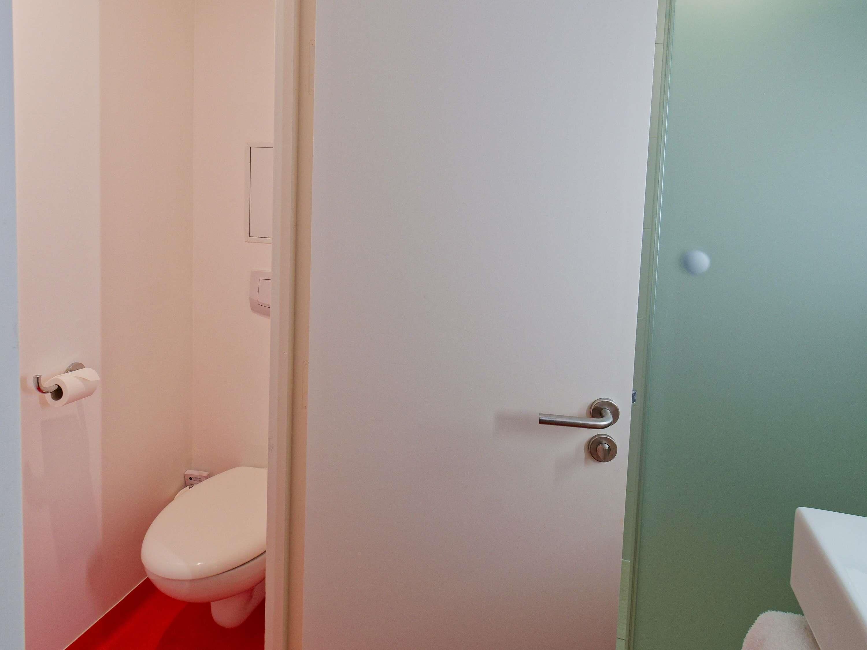 A bathroom with a toilet, a sink, and a door.