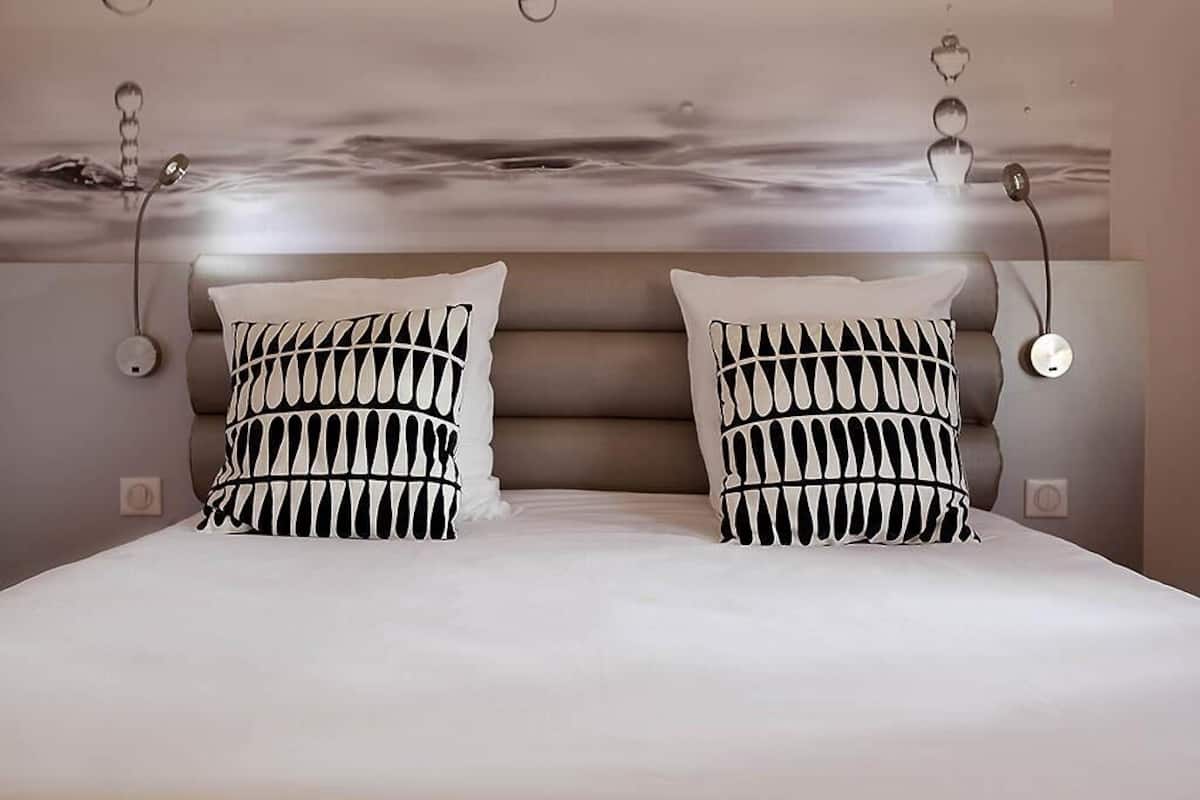 A bedroom with a large bed, two patterned pillows, and a modern headboard.