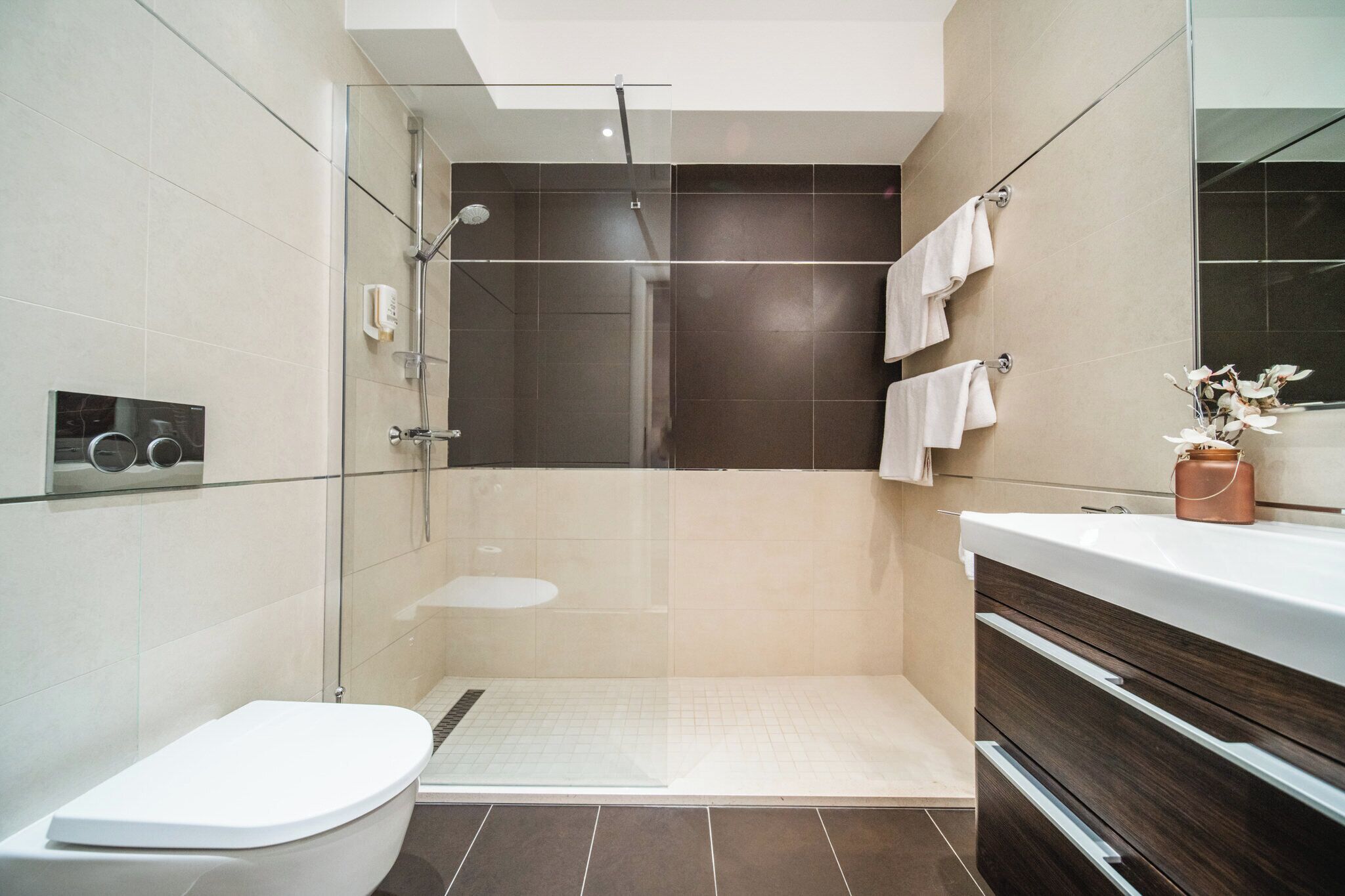 A modern bathroom with a glass-enclosed shower, a white toilet, and a vanity with a mirror.