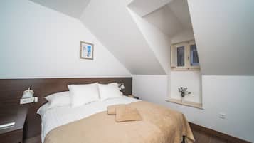 Een slaapkamer met een groot bed, nachtkastje, een klein plankje met een plantje.