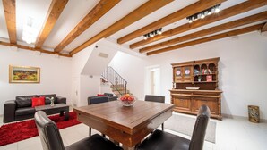 A dining area with a wooden table and chairs, a red rug, and a black leather sofa. - Celenga Apartments with free offsite parking (Dubrovnik)