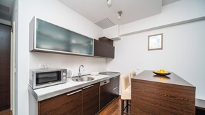 A compact kitchen with a microwave, sink, and wooden cabinets. - Celenga Apartments with free offsite parking (Dubrovnik)
