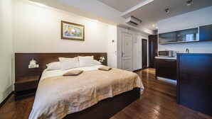A modern hotel room with a large bed, a bedside table, a microwave, and a small kitchenette. - Celenga Apartments with free offsite parking (Dubrovnik)