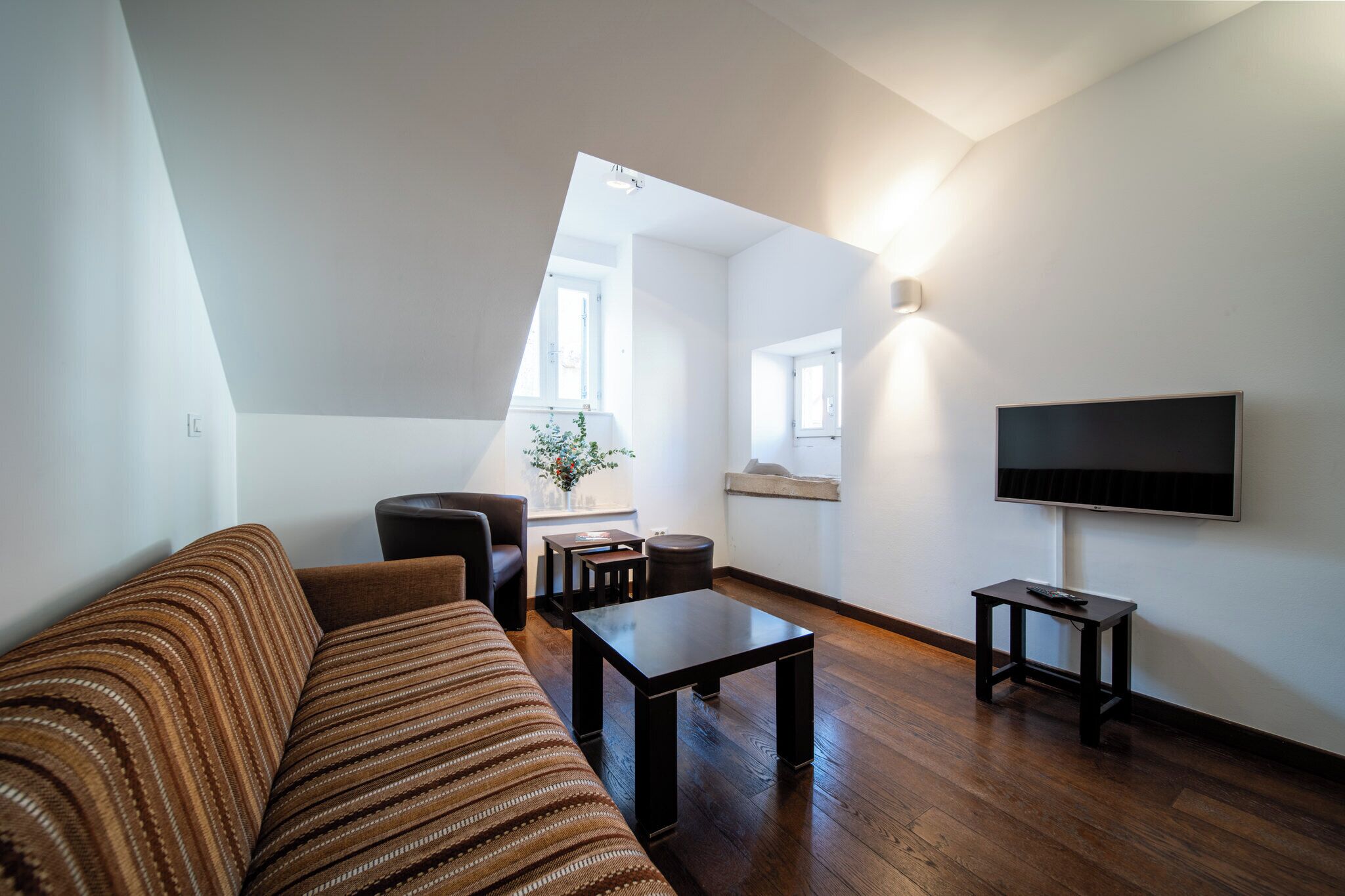 Un salón moderno con sofá, mesa de centro y televisor. Se ve una ventana con vistas al exterior.