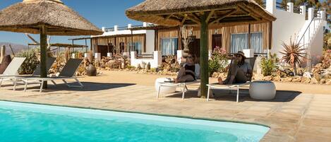 Una piscina al aire libre, sombrillas, sillones reclinables de piscina