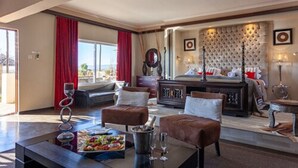 A hotel room with a large bed, a sitting area with a table, and a view of the outdoors. - Inverdoorn Private Game Reserve (Breede River)