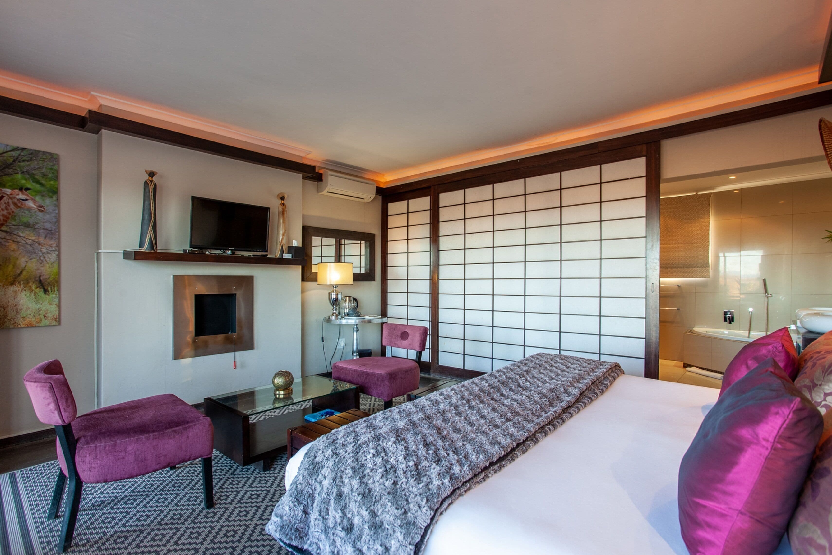 Ein Hotelzimmer mit Bett, Schreibtisch mit Computer, Stuhl, Fernseher und einem großen Fenster mit Blick.
