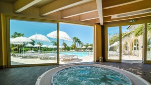 Un área de spa con hidromasaje, ventanas amplias y vista a la piscina.