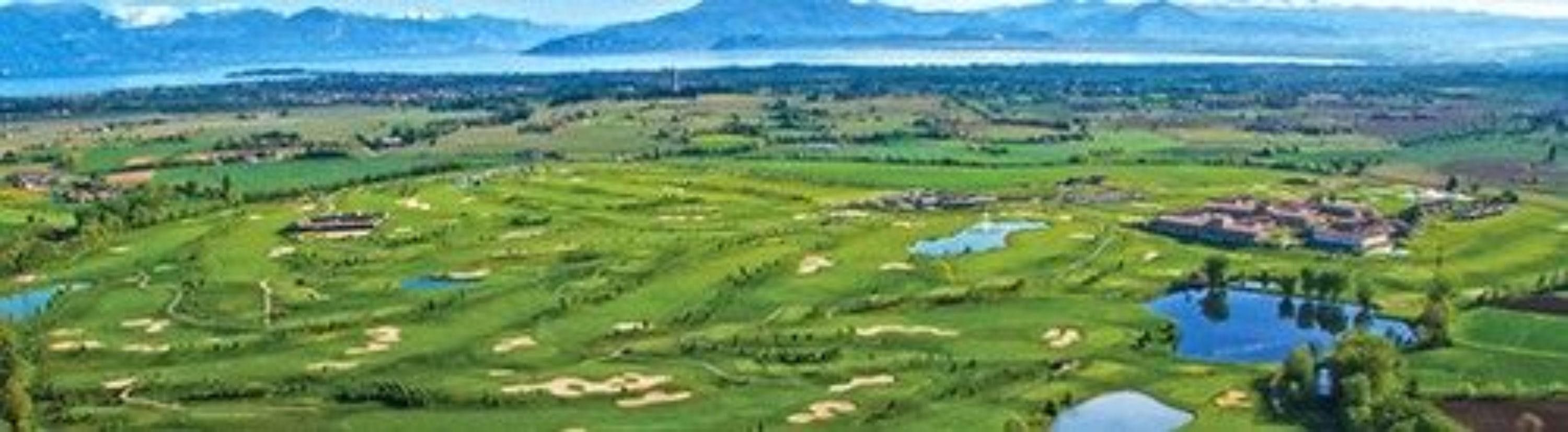 A golf course with multiple holes, water bodies, and a mountainous backdrop.