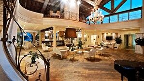 Un interior espacioso de varios niveles con una escalera imponente, muebles elegantes y un piano.