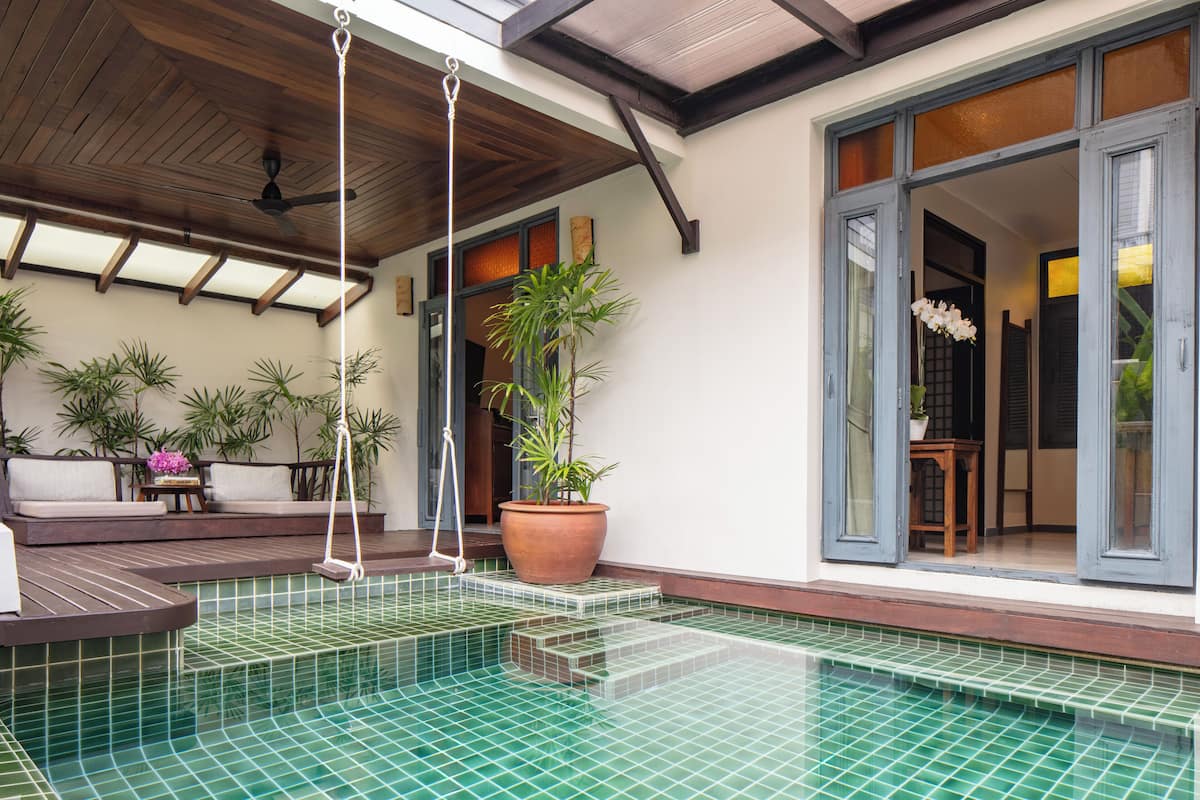 A swimming pool with a tiled floor, a wooden ceiling, and a hanging swing.