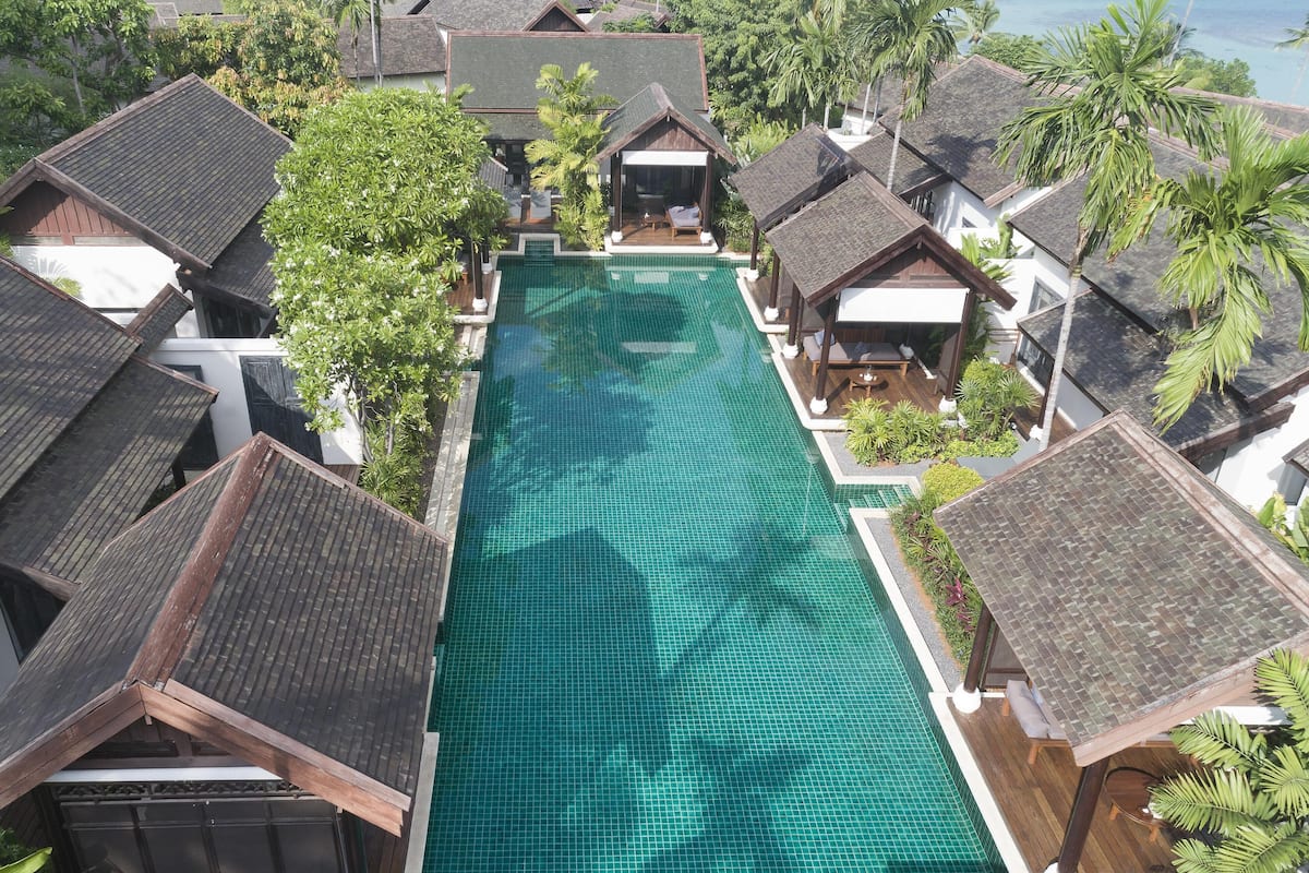 A resort with a central swimming pool, multiple bungalow-style buildings, and lush tropical vegetation.