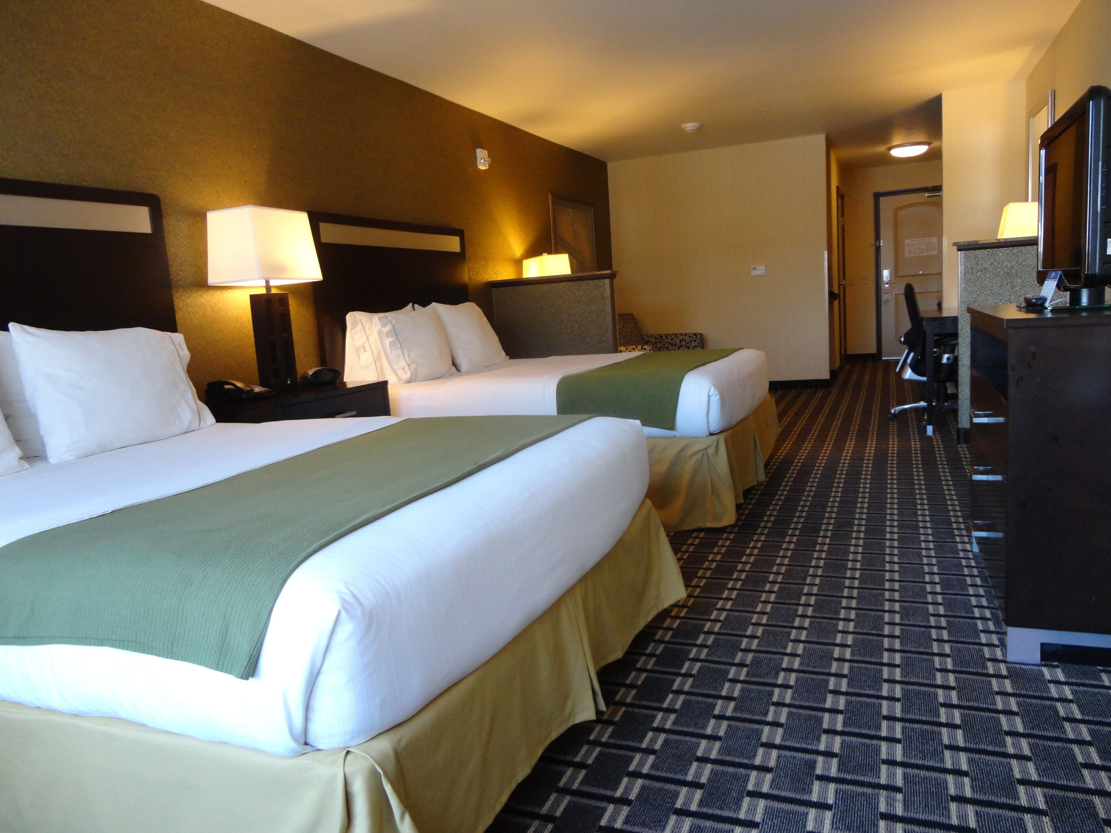 A hotel room with two beds, a desk, and a reception area.
