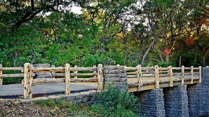 A wooden bridge with stone pillars, surrounded by dense greenery and trees. - Best Way Inn Cleburne TX (Cleburne)