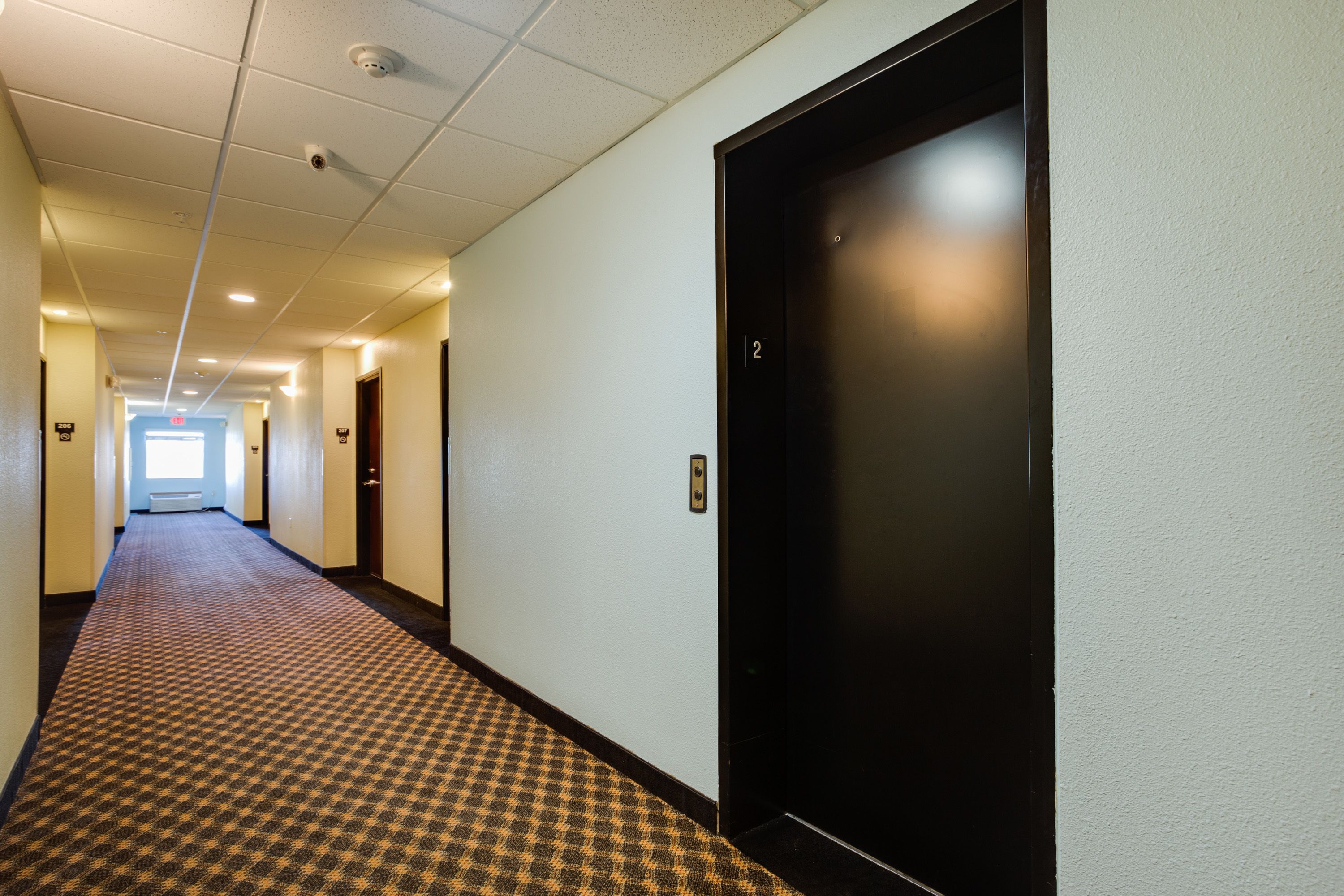 A hotel hallway with a patterned carpet, a black elevator door, and a visible door number '2'.