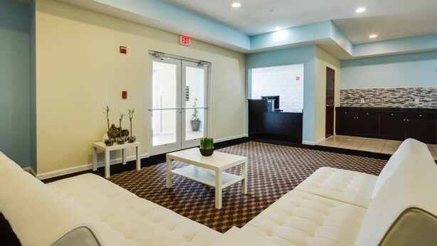 A lobby with a checkered floor, white sofas, a small table with a plant, and a reception desk. - Best Way Inn Cleburne TX (Cleburne)