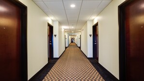 A hotel hallway with carpeted floors, wooden doors, and a ceiling with recessed lighting. - Best Way Inn Cleburne TX (Cleburne)