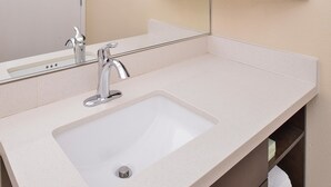 Une salle de bain avec un lavabo blanc, un miroir et une porte.