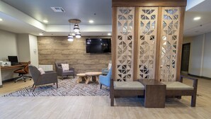 Un espace de détente moderne avec un mur en bois, un téléviseur à écran plat et un aménagement comprenant un canapé, des fauteuils et une table basse.