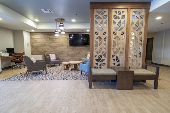Un área de estar moderna con una pared de madera, un televisor de pantalla plana y un conjunto de asientos que incluye un sofá, sillas y una mesa de centro.