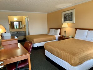 A hotel room with two beds, a desk, a chair, a lamp, a phone, and a painting on the wall. - Regency Inn Fairfield (Fairfield)